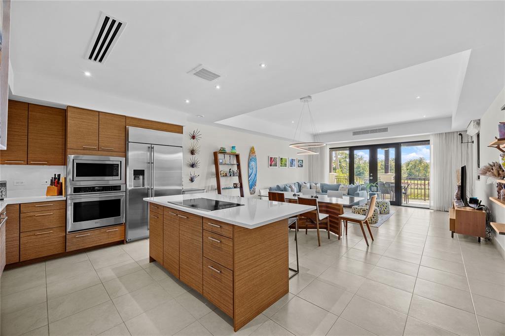 A modern kitchen with wood cabinets and a central island opens to a dining area — 7000 BAHIA BEACH DR UNIT 7258, RIO GRANDE, PR