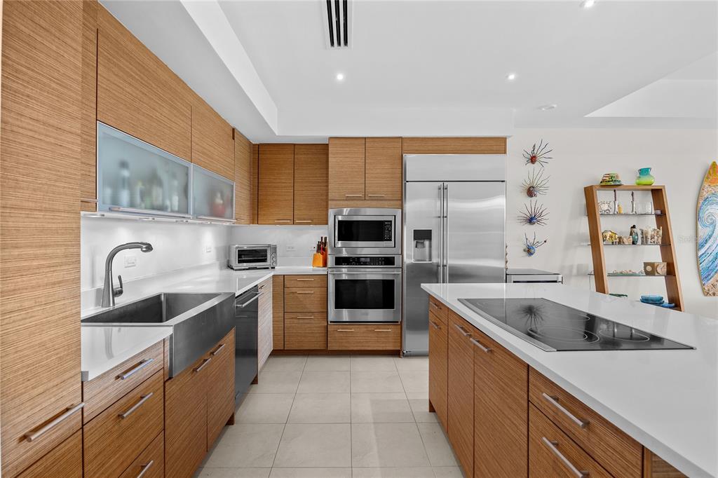 A modern kitchen features wood-grain cabinets, stainless steel appliances, white countertops, and a center island — 7000 BAHIA BEACH DR UNIT 7258, RIO GRANDE, PR