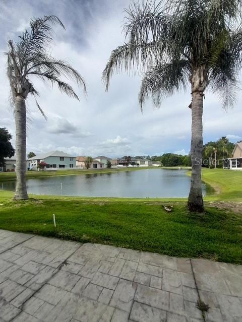 A white house exterior features a screened-in patio with sliding glass doors and a concrete patio — 2614 CAITHNESS WAY, CLERMONT, FL
