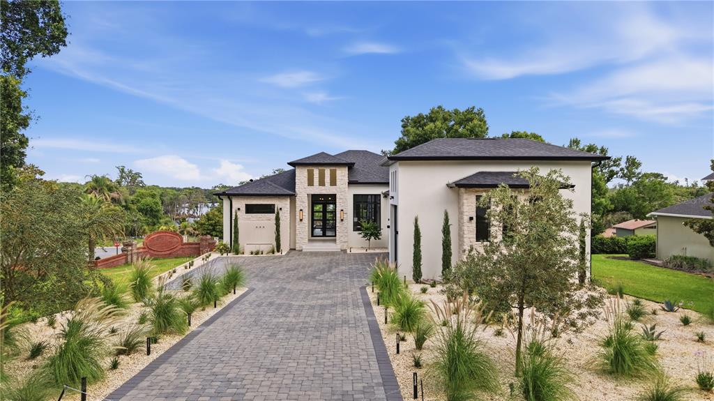 A modern house with a stone facade, dark roof, and a paved driveway — 11500 OSPREY POINTE BOULEVARD, CLERMONT, FL