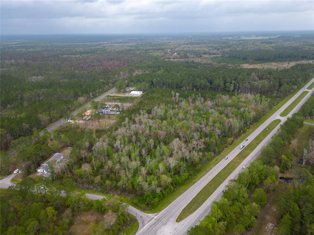 An aerial view shows a wooded lot bordered by a highway and a residential road — TBD NE WALDO ROAD, GAINESVILLE, FL