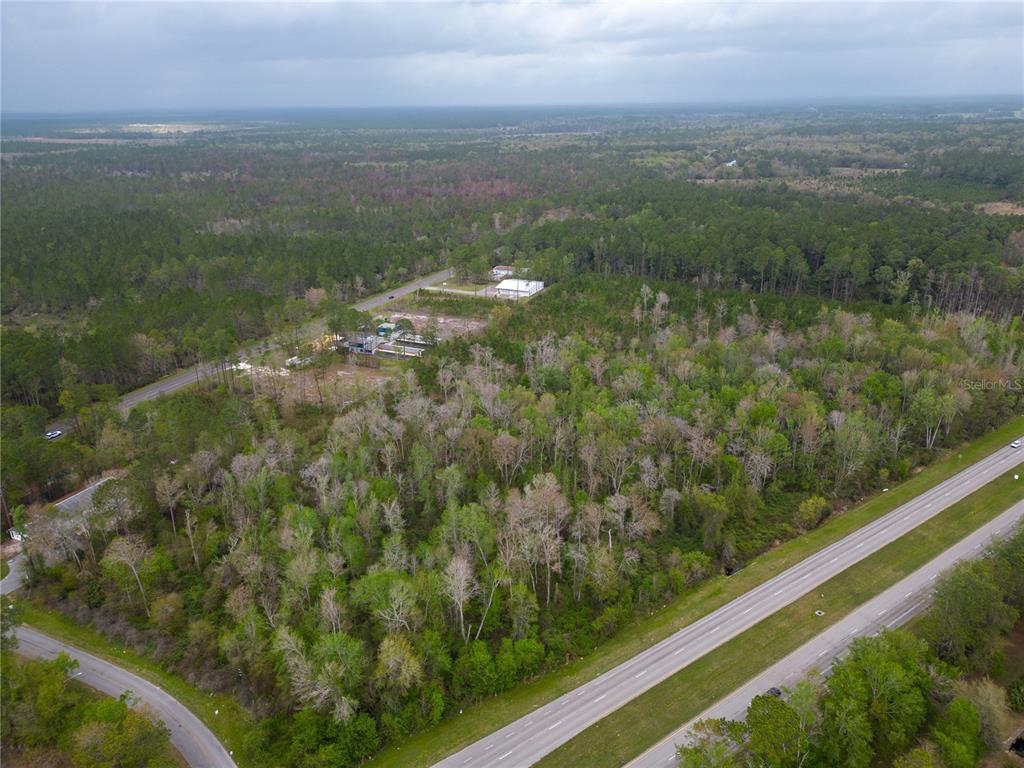 An aerial view shows a wooded lot situated between a highway and a paved road — TBD NE WALDO ROAD, GAINESVILLE, FL