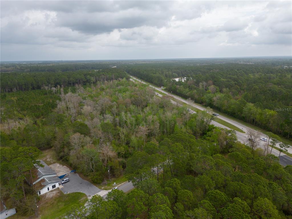 An aerial view shows a wooded lot next to a road with a small building — TBD NE WALDO ROAD, GAINESVILLE, FL