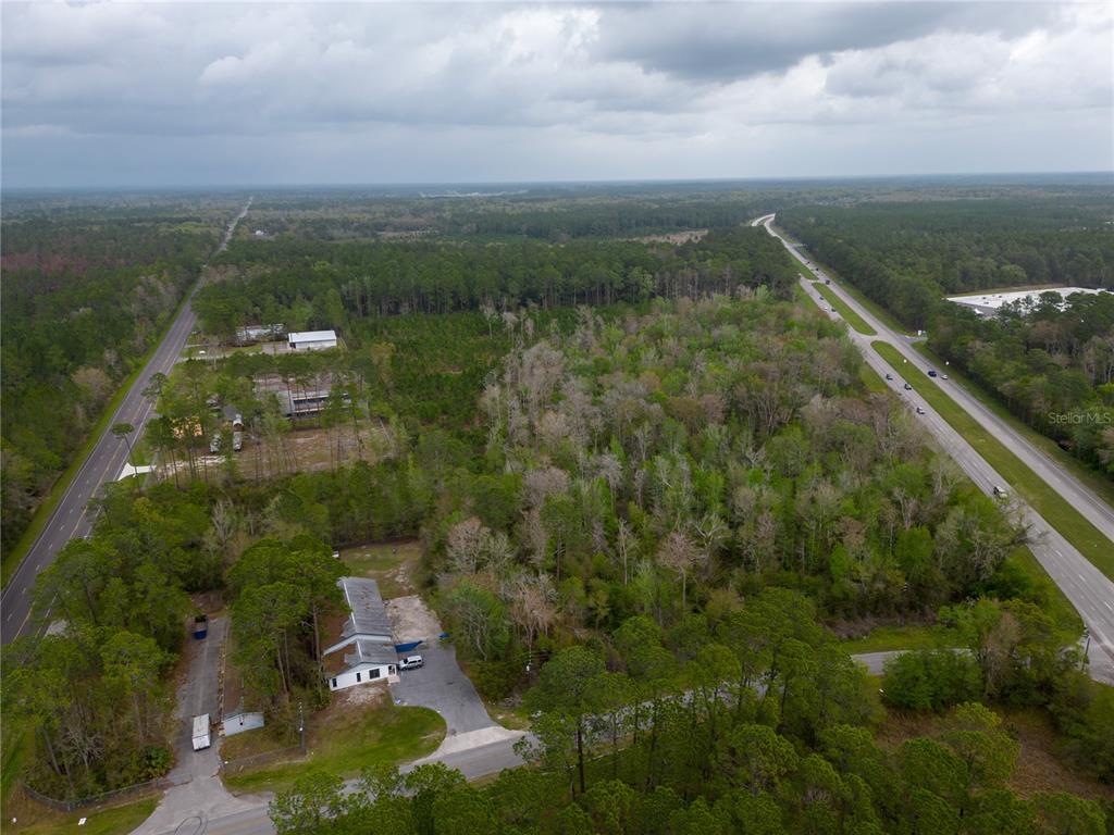 An aerial view shows a wooded lot situated between two roads with a small building — TBD NE WALDO ROAD, GAINESVILLE, FL