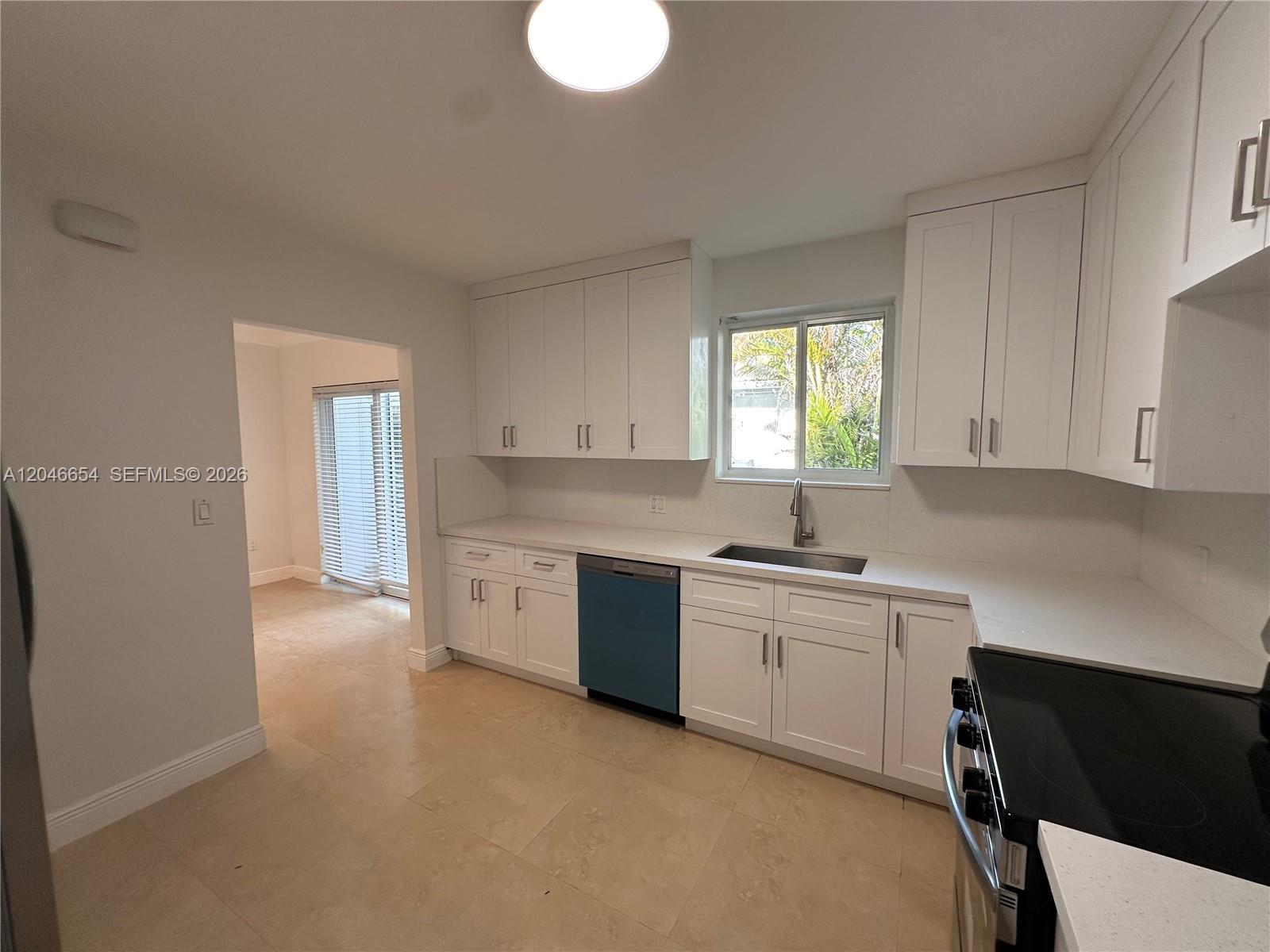 A kitchen features white cabinets, light countertops, a blue dishwasher, and beige tile flooring — 1130 Cotorro Ave # 1130, Coral Gables FL 33146, CORAL GABLES, FL