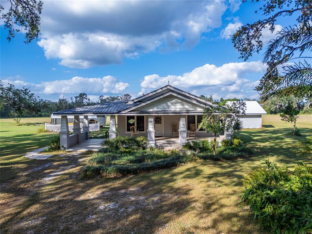 A single-story house with a metal roof, front porch, and carport sits on a grassy lot — 5020 SYDNEY ROAD, PLANT CITY, FL