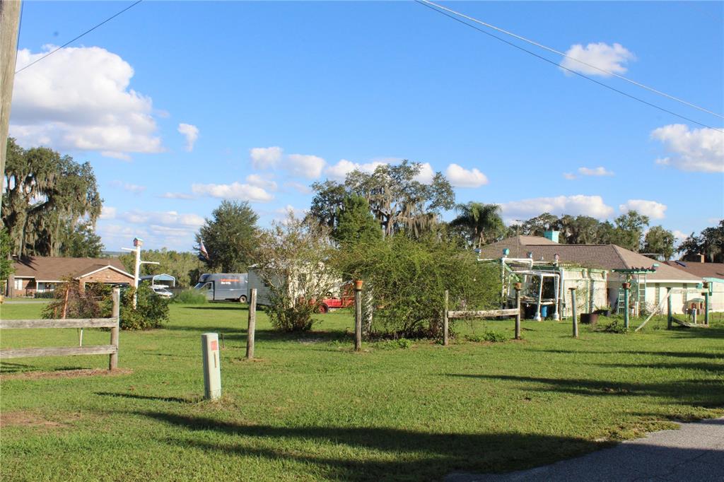 A light green single-story house with a concrete driveway and a brown shingled roof — 38901 ELLA DRIVE, LADY LAKE, FL