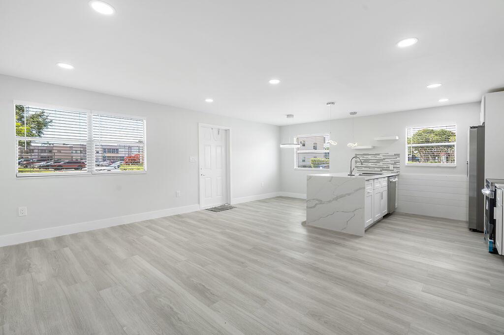 A bright, open-concept kitchen and living area featuring light wood floors and a marble island — 385 Flanders I, Delray Beach FL 33484, DELRAY BEACH, FL