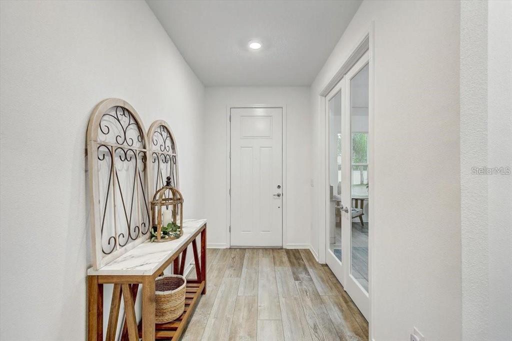 A bright entryway features wood-look flooring, a white front door, and a marble-topped console table — 2824 QUAIL CREST COURT, VALRICO, FL