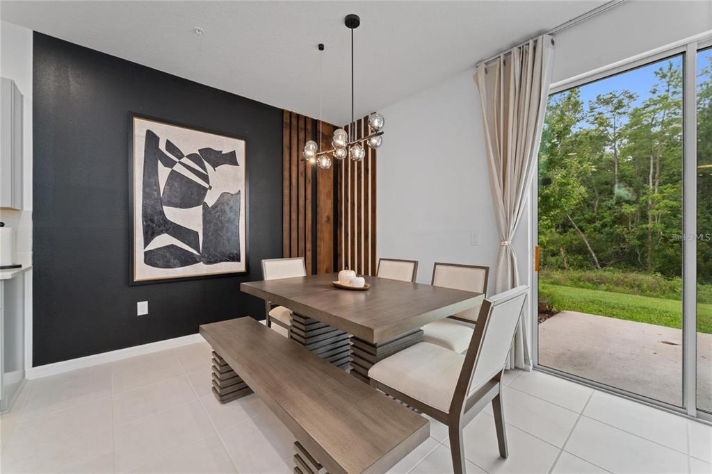 A dining room features a wooden table with a bench, chairs, and a black accent wall — 2125 CRYSTAL BELL STREET, ORLANDO, FL
