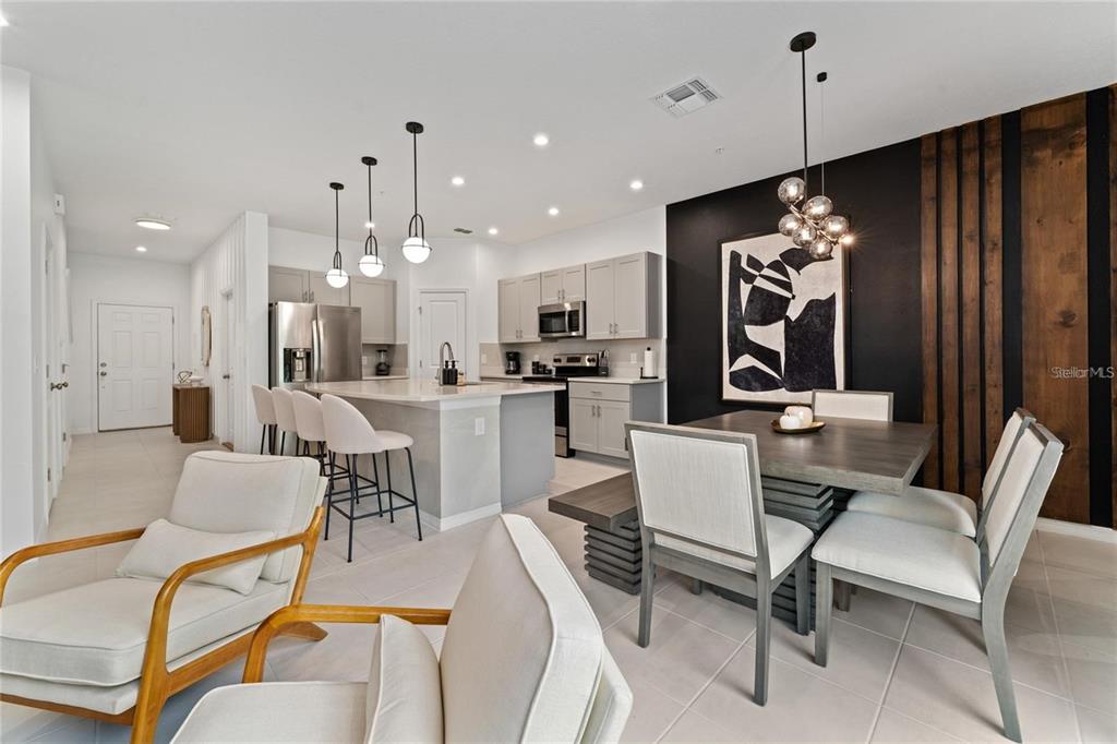 An open-concept kitchen and dining area features light cabinetry, a kitchen island, and wood accents — 2125 CRYSTAL BELL STREET, ORLANDO, FL