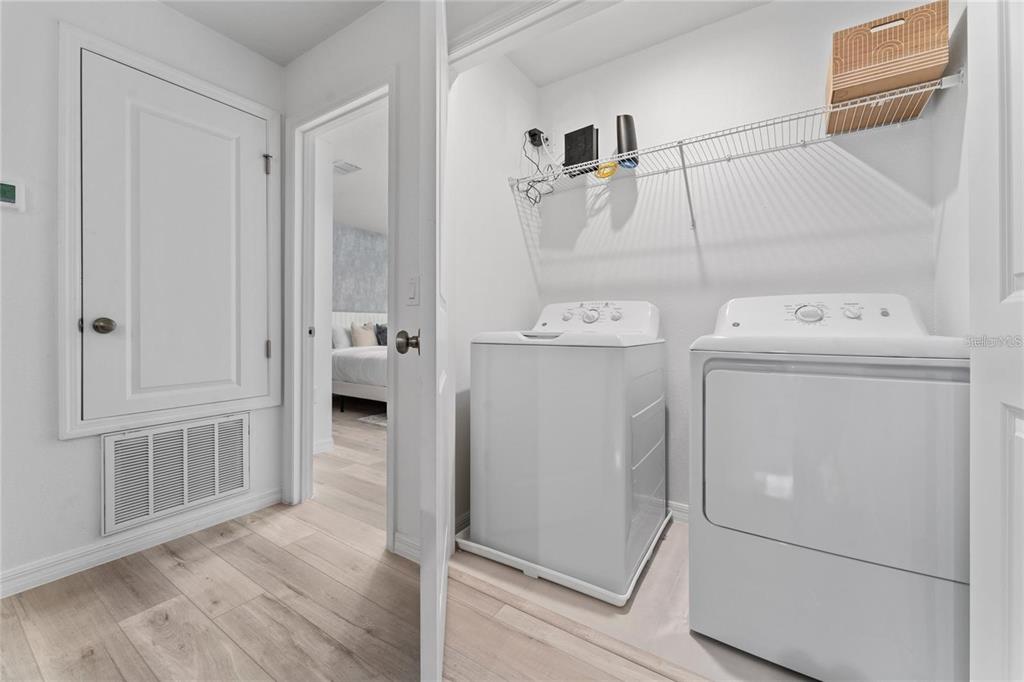 A laundry closet with a white washer and dryer sits beside a hallway and bedroom — 2125 CRYSTAL BELL STREET, ORLANDO, FL