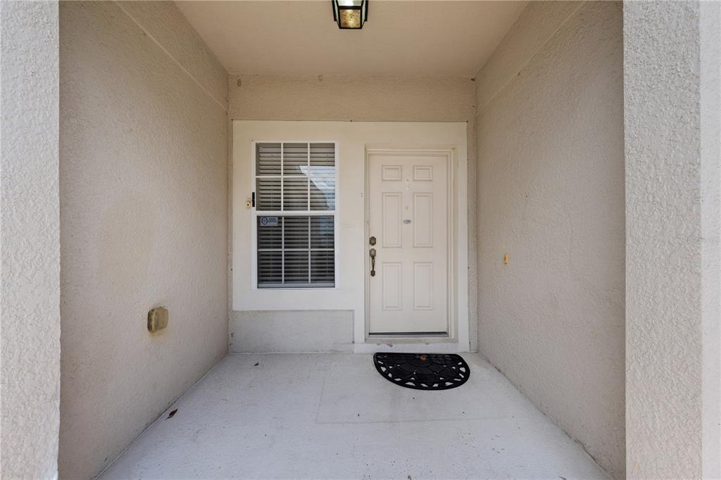 A covered entryway features a white front door, a single window, and a concrete floor — 3313 PEKIN STREET, ST CLOUD, FL