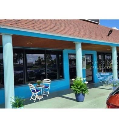 A blue building exterior features a covered porch with white columns and outdoor seating — 3496 TAMIAMI TRAIL, PORT CHARLOTTE, FL