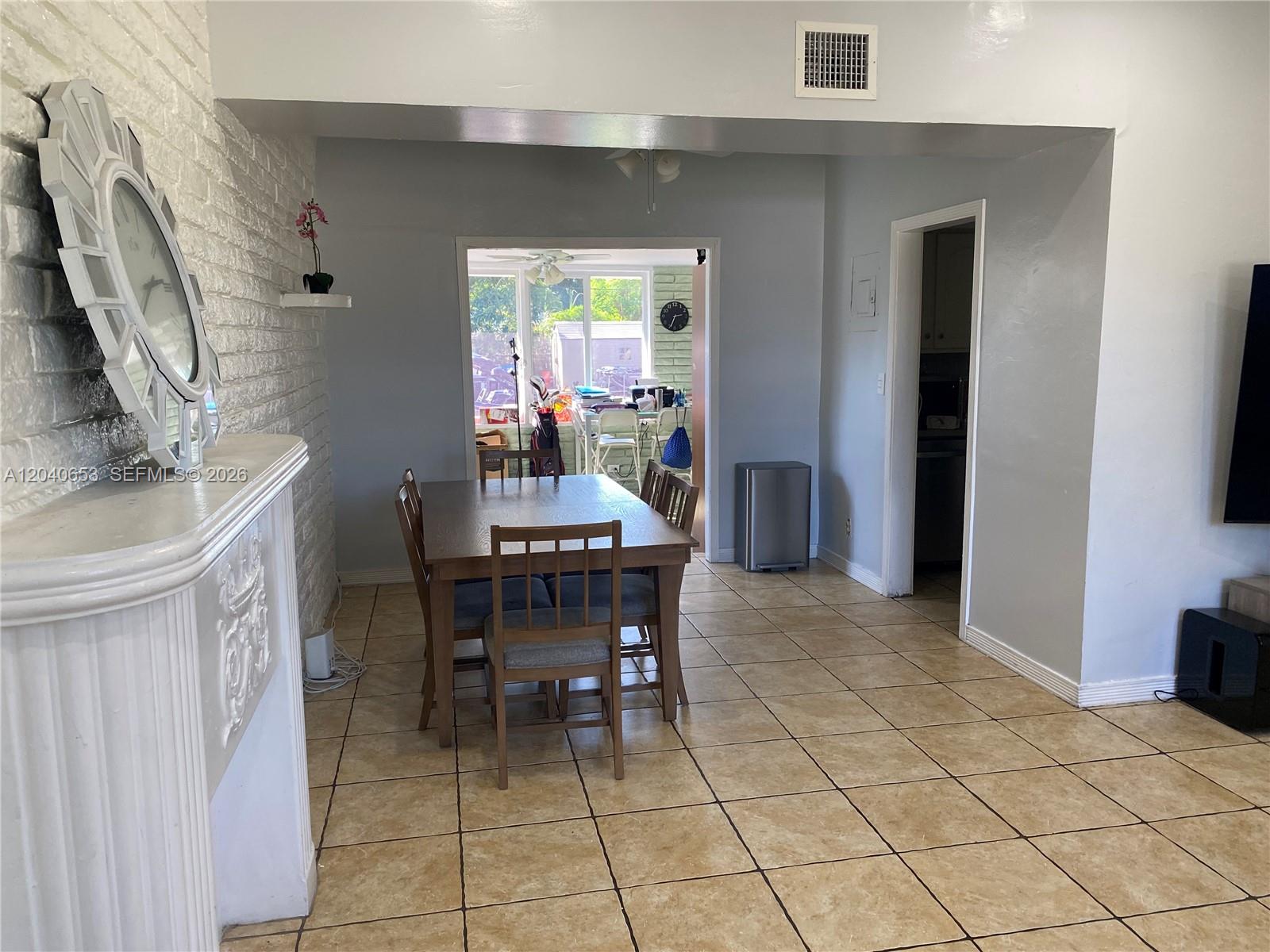 A dining area with a wooden table and chairs sits before a sunroom entrance — 540 NW 111 St, Miami FL 33168, MIAMI, FL