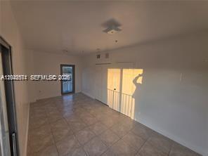 An empty room with light-colored tile flooring, white walls, and a glass door — 2389 NW 26th St # 2B, Miami FL 33142, MIAMI, FL