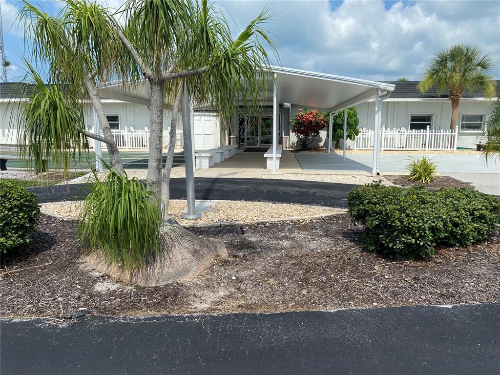 A covered walkway leads to the entrance of a building with a palm tree nearby — 181 S FIJI CIRCLE UNIT 181, ENGLEWOOD, FL