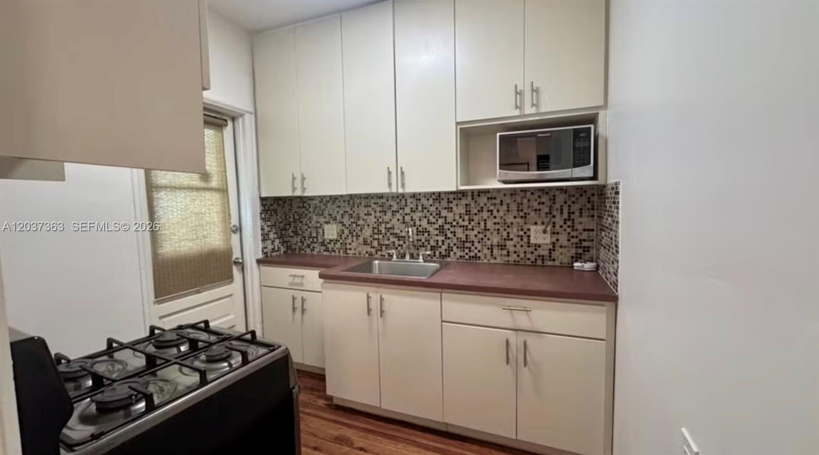 A kitchen features white cabinets, a dark countertop, a stainless steel sink, and a microwave — 751 Euclid Ave # 2, Miami Beach FL 33139, MIAMI BEACH, FL