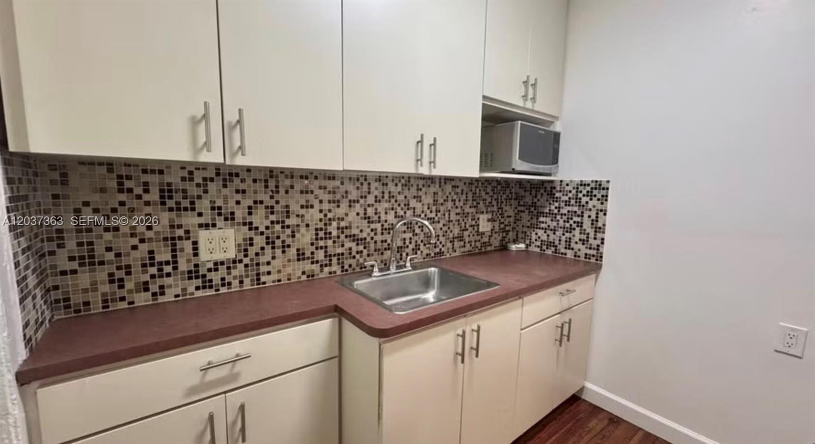 A kitchen features white cabinets, a stainless steel sink, and a brown mosaic tile backsplash — 751 Euclid Ave # 2, Miami Beach FL 33139, MIAMI BEACH, FL