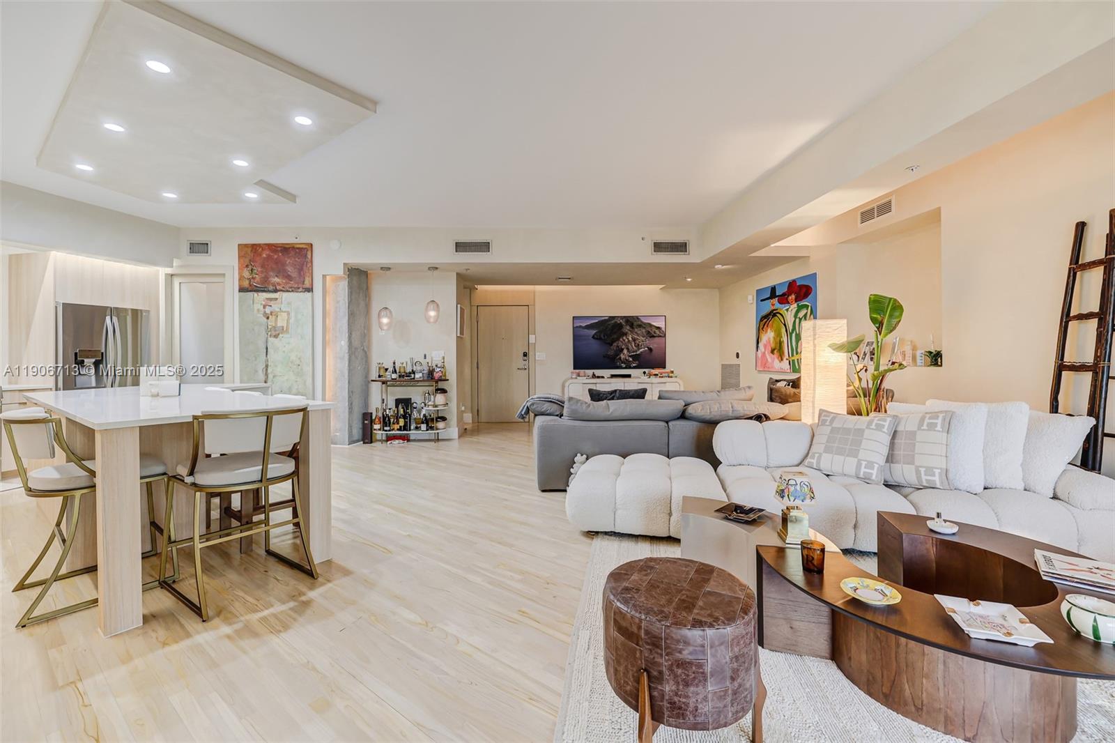 An open-concept living area features a kitchen island, white sofa, and light wood flooring — 2001 Meridian Ave # 307, Miami Beach FL 33139, MIAMI BEACH, FL