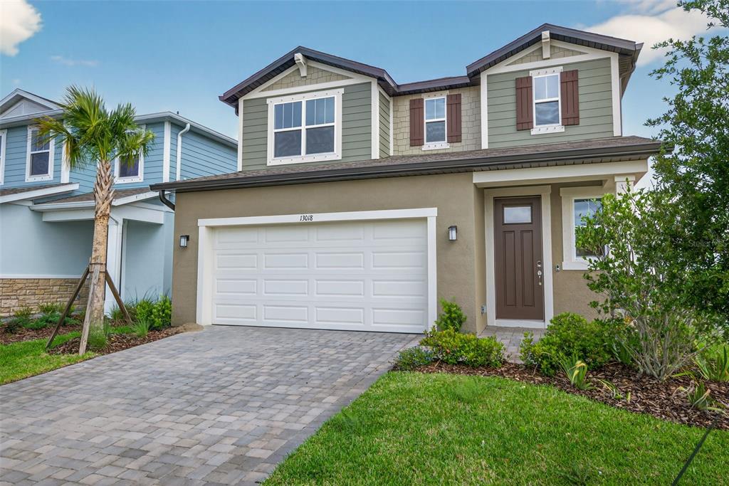 A two-story house with a tan stucco exterior, green siding, and a two-car garage — 13018 SUNSEED STREET, PARRISH, FL