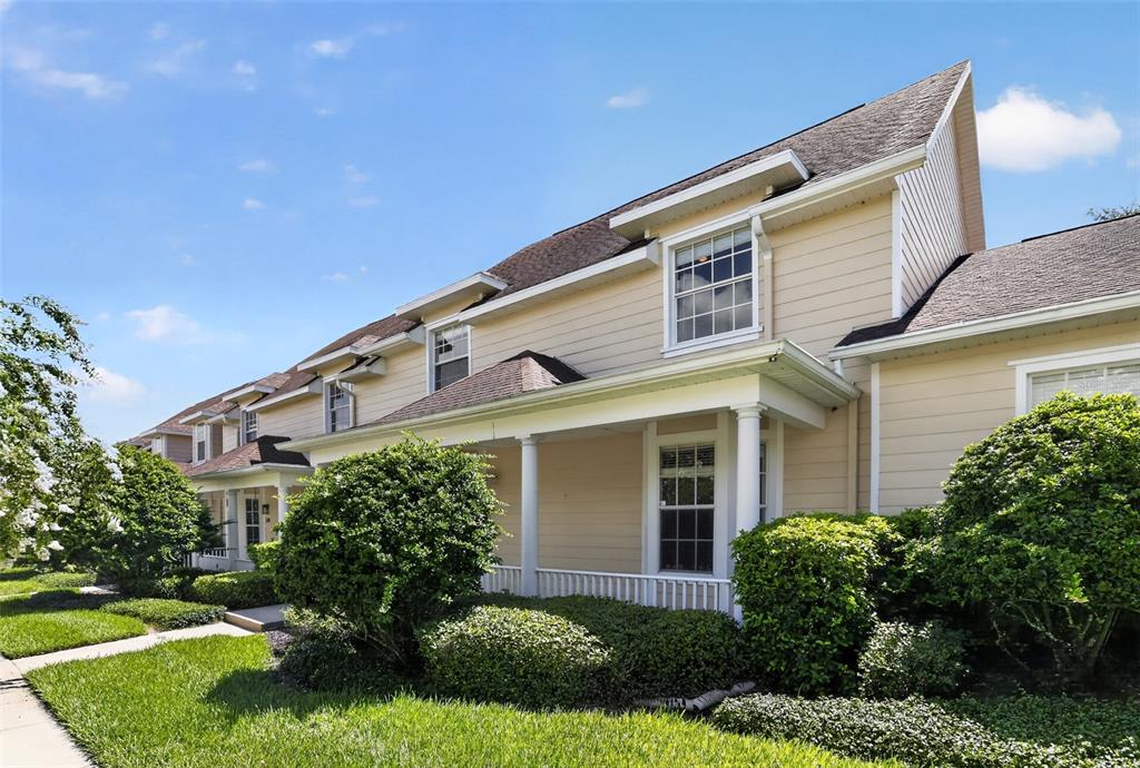 A beige two-story townhouse with a covered front porch and manicured landscaping — 332 NAUTICA MILE DRIVE, CLERMONT, FL
