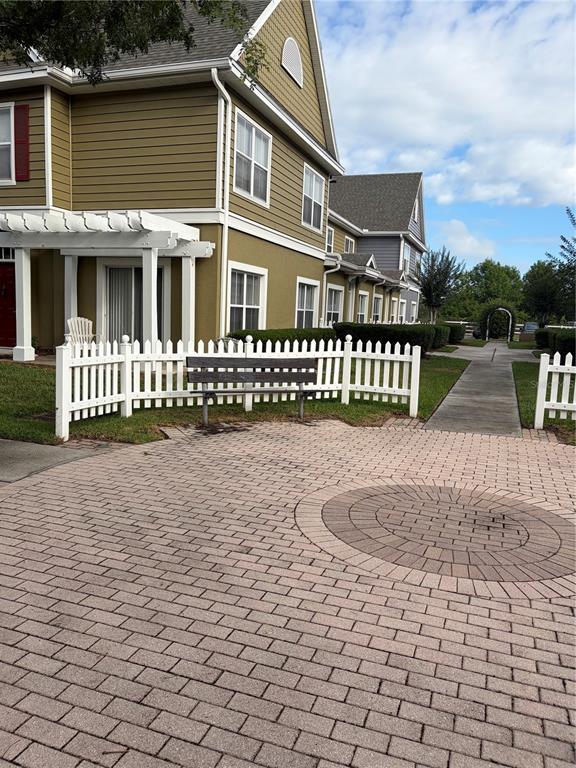 A paved patio features a bench, a white picket fence, and a multi-story building exterior — 2610 LODI CIRCLE UNIT 102, KISSIMMEE, FL