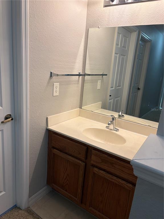 A bathroom vanity features a wooden cabinet, a white countertop, and a wall-mounted mirror — 2610 LODI CIRCLE UNIT 102, KISSIMMEE, FL