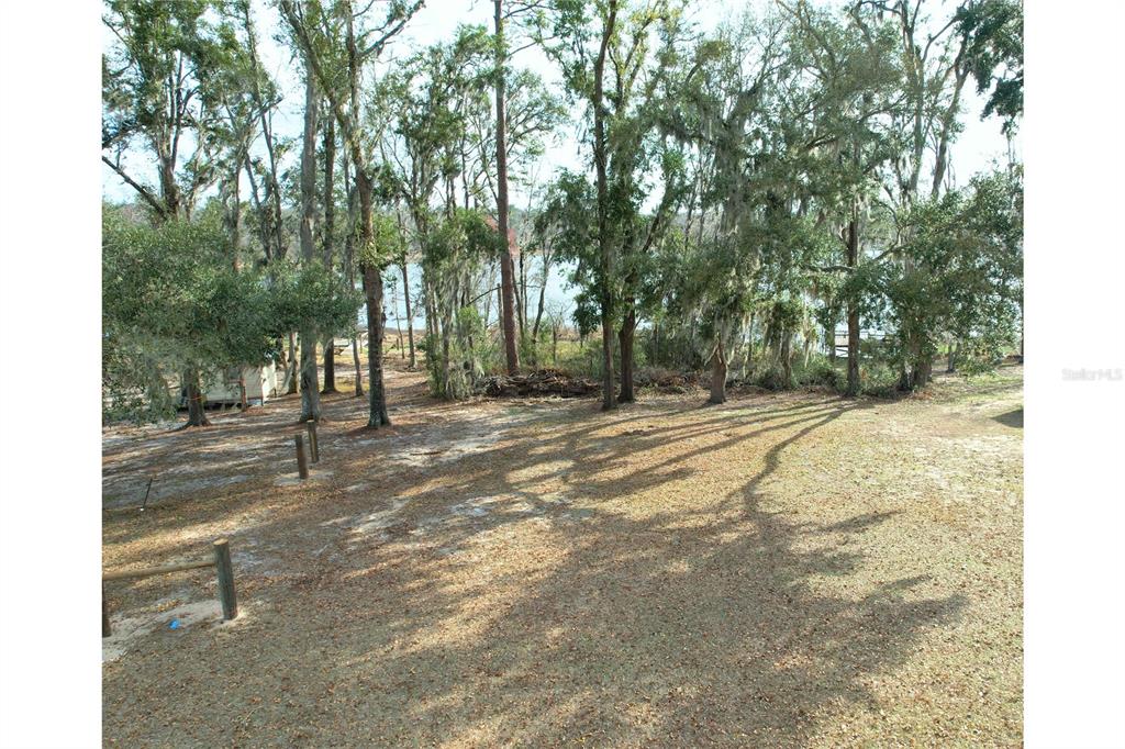 A grassy yard with scattered trees leads toward a body of water in the distance — 00 NW BUR OAK PLACE, JENNINGS, FL