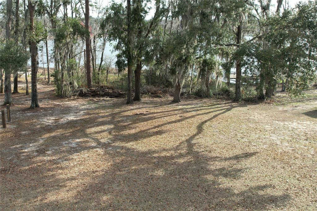 A grassy yard with scattered leaves and trees leads to a view of the water — 00 NW BUR OAK PLACE, JENNINGS, FL