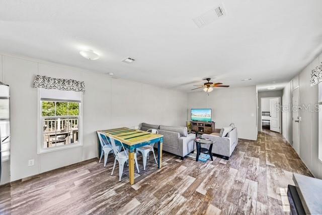 A living and dining area features wood-look flooring, a gray sofa, and a wooden table — 14418 STEPHENS ROAD, PORT CHARLOTTE, FL