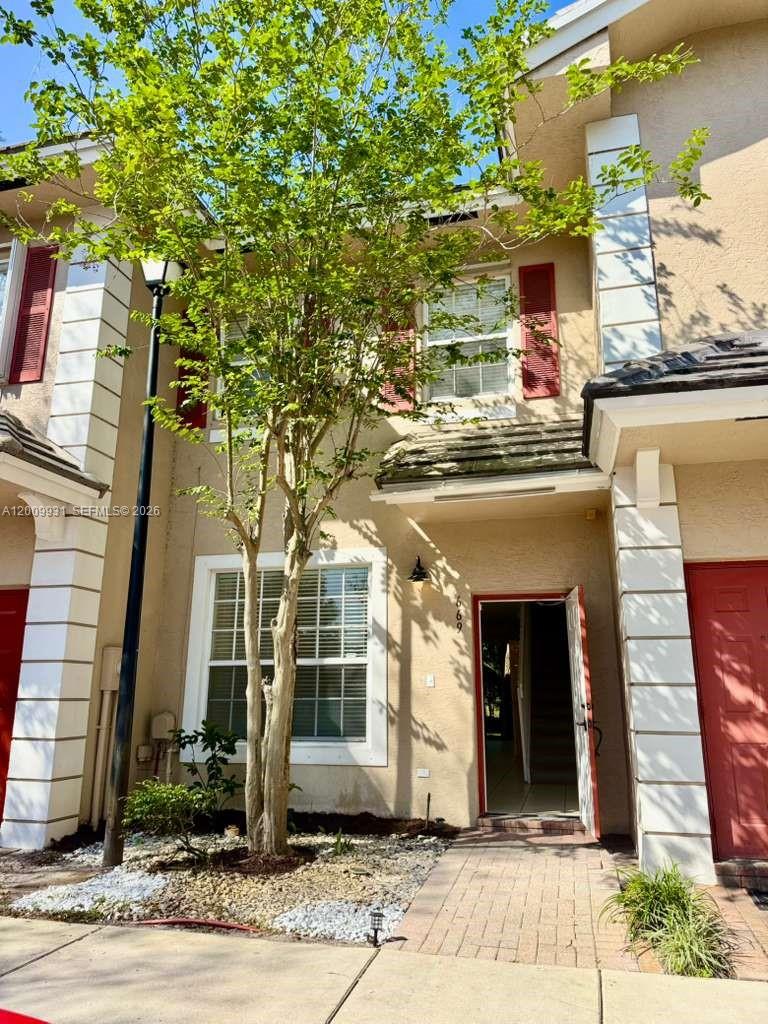 A two-story townhouse exterior features a tan facade, red shutters, and a front entrance — 669 NW 42nd Ave, Plantation FL 33317, PLANTATION, FL