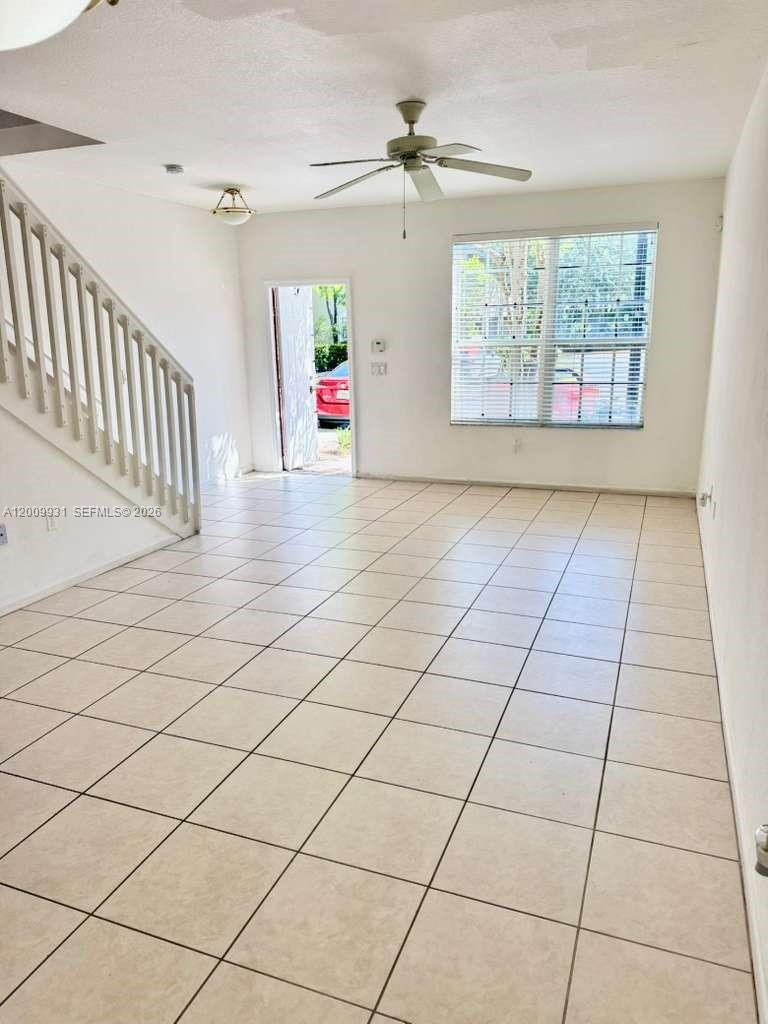 An empty room features white walls, light-colored tile flooring, a ceiling fan, and a staircase — 669 NW 42nd Ave, Plantation FL 33317, PLANTATION, FL
