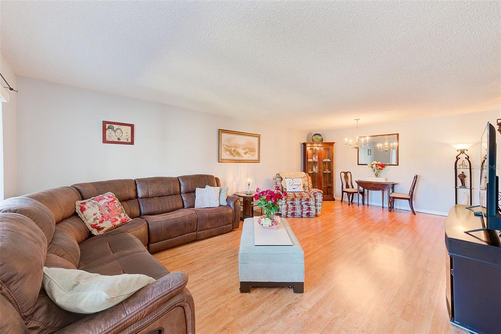 A living room features a brown sectional sofa, light wood flooring, and a dining area — 2229 AMERICUS BOULEVARD W UNIT 25, CLEARWATER, FL