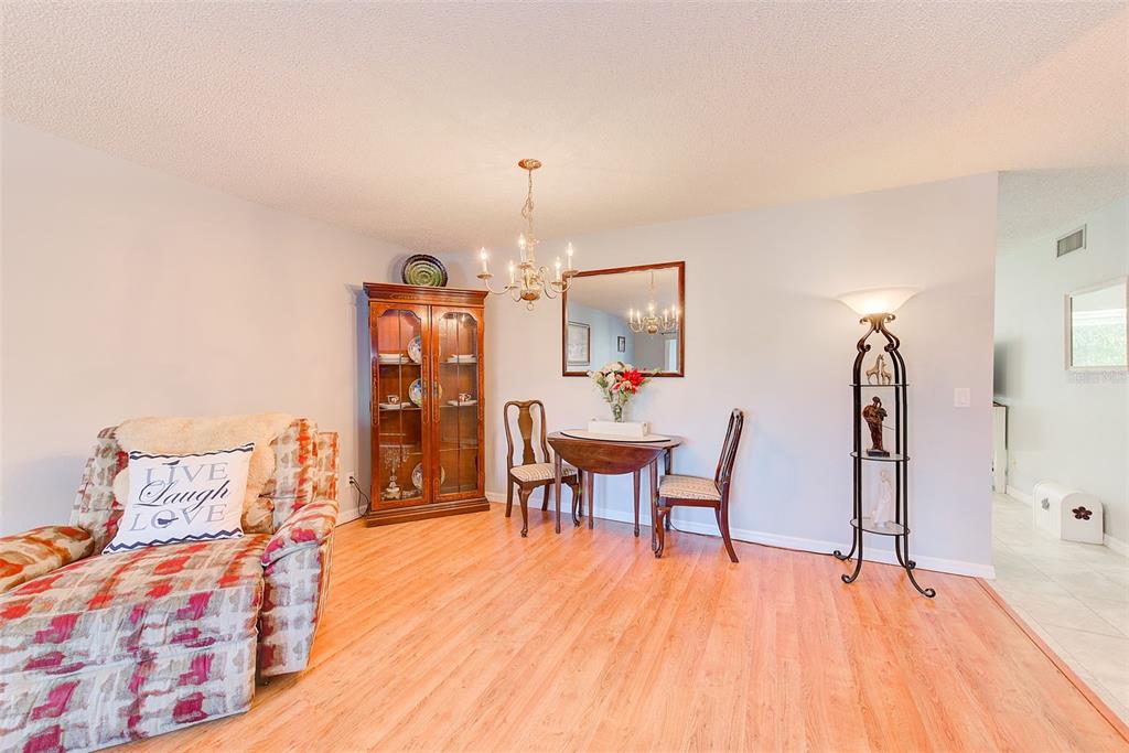 A dining area with a wood hutch, small table, and patterned armchair on wood flooring — 2229 AMERICUS BOULEVARD W UNIT 25, CLEARWATER, FL