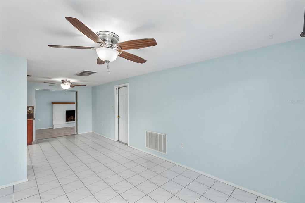 A room with light blue walls, white tile flooring, and two ceiling fans — 3128 KILBURN ROAD, HOLIDAY, FL