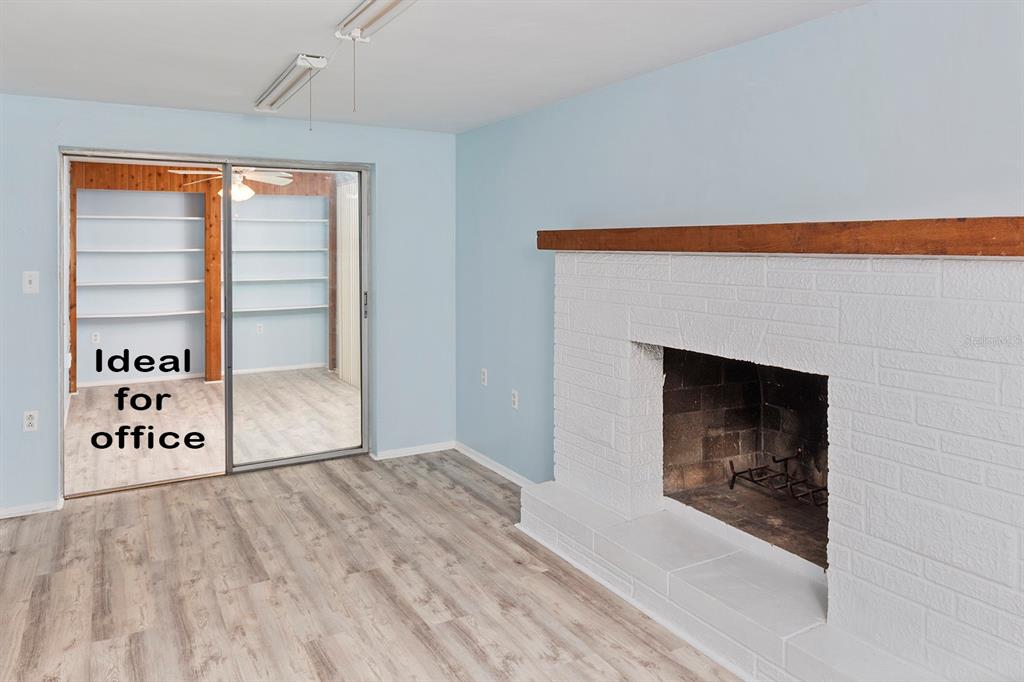A room with light blue walls, wood-look flooring, and a white brick fireplace with a mantel — 3128 KILBURN ROAD, HOLIDAY, FL