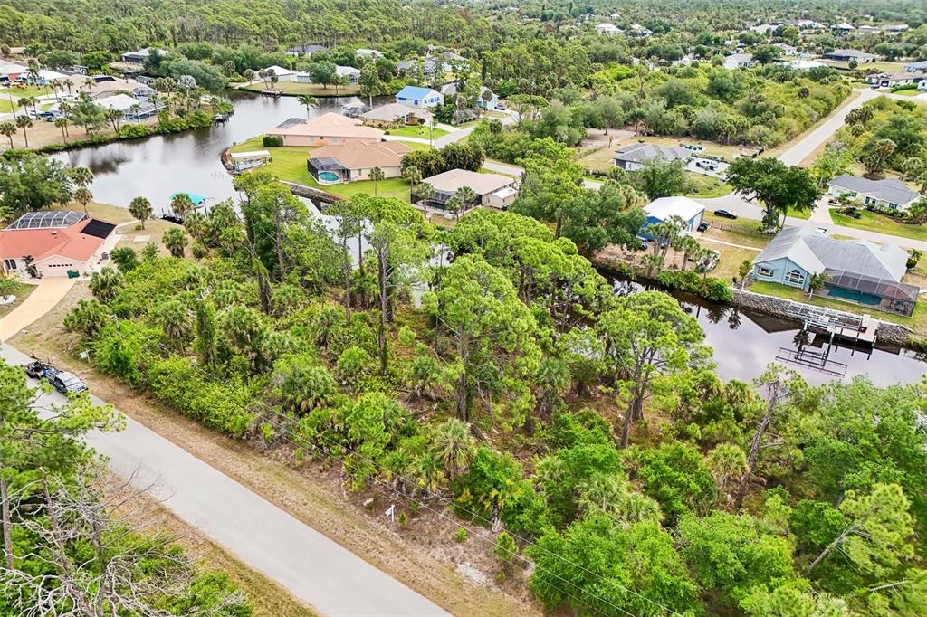An aerial view shows a wooded residential lot situated between two canals in a neighborhood — 1168 ANAHEIM STREET, PORT CHARLOTTE, FL