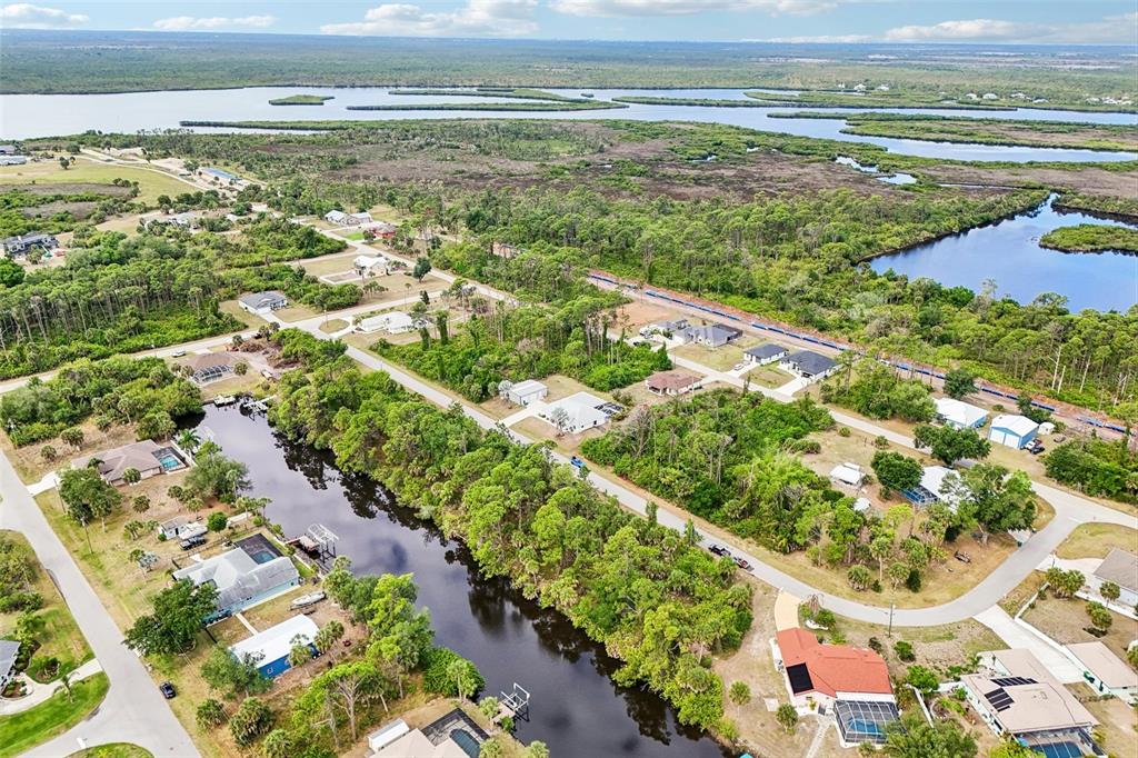 An aerial view shows houses situated along a canal surrounded by dense trees and water — 1168 ANAHEIM STREET, PORT CHARLOTTE, FL