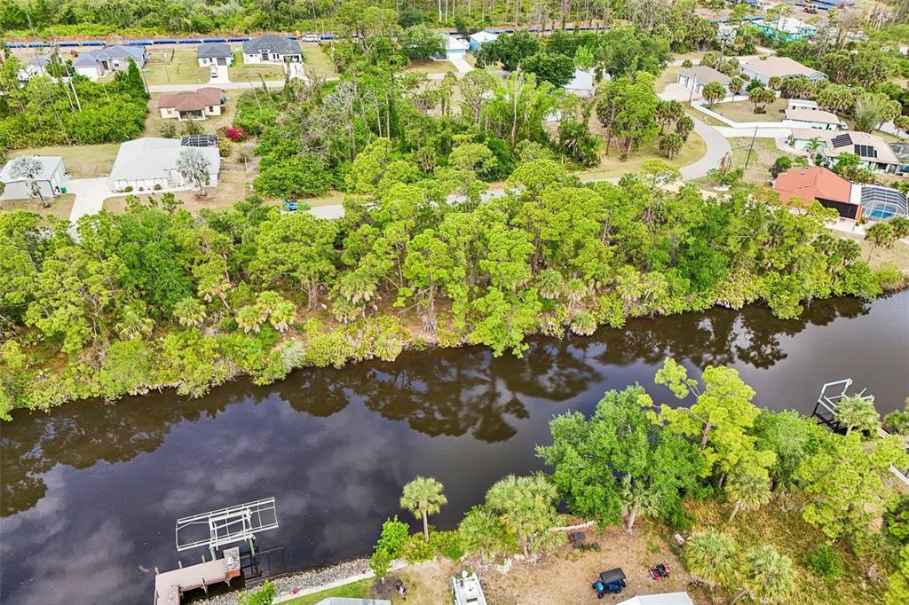 An aerial view shows a canal bordered by trees and several residential houses — 1168 ANAHEIM STREET, PORT CHARLOTTE, FL