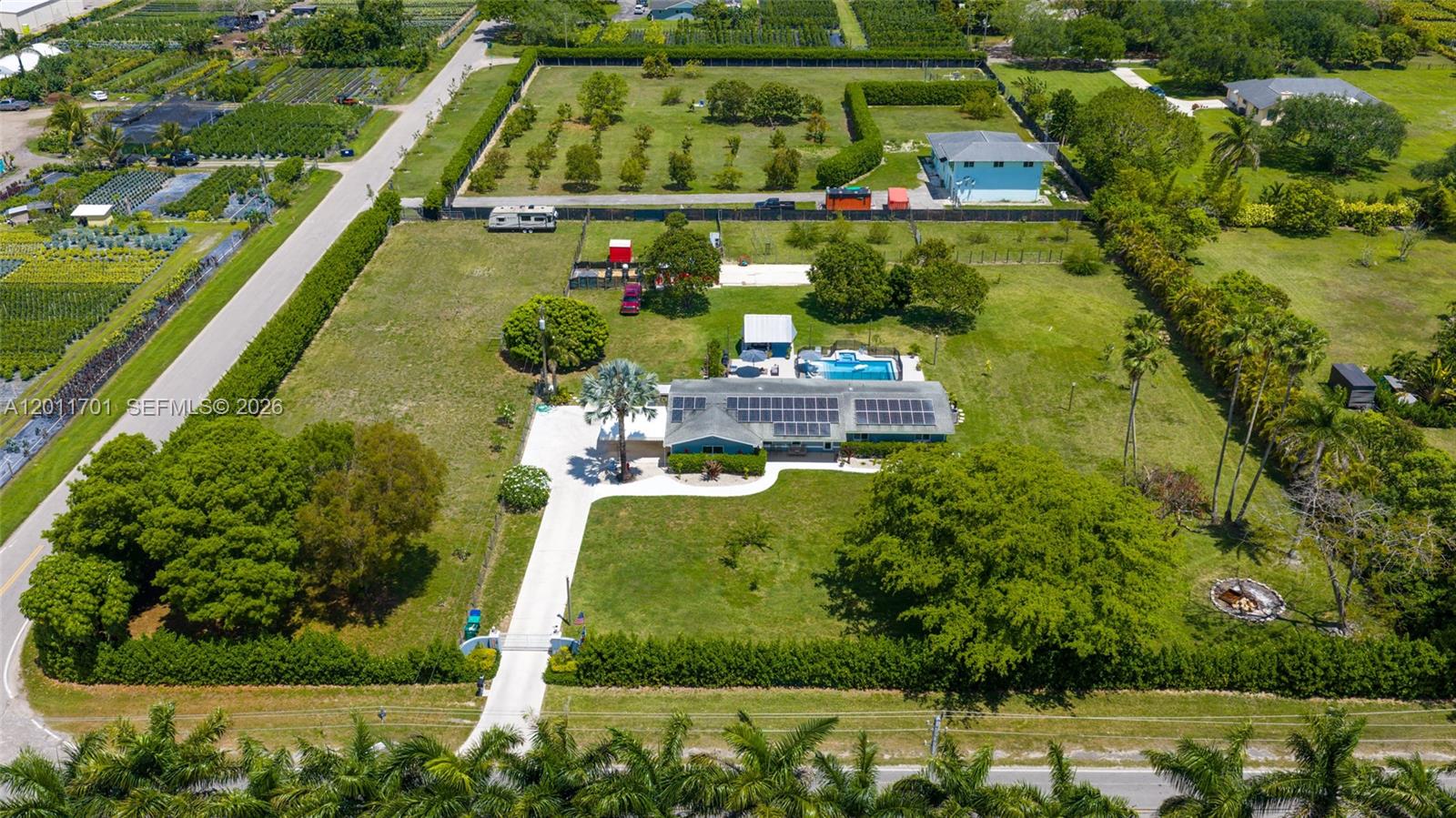 An aerial view shows a house with solar panels, a pool, and a large yard — 21175 SW 232nd St, Miami FL 33170, MIAMI, FL
