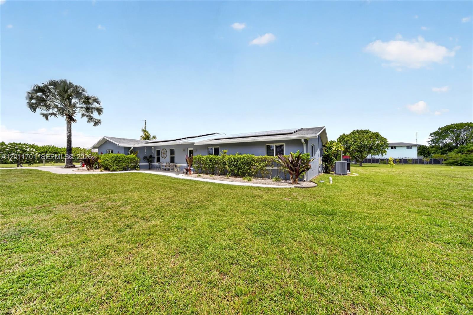 A single-story gray house with solar panels sits on a large, grassy lot — 21175 SW 232nd St, Miami FL 33170, MIAMI, FL