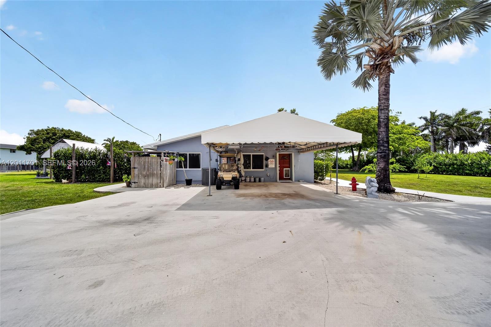 A light blue house features a large white canopy covering a concrete driveway and entrance — 21175 SW 232nd St, Miami FL 33170, MIAMI, FL