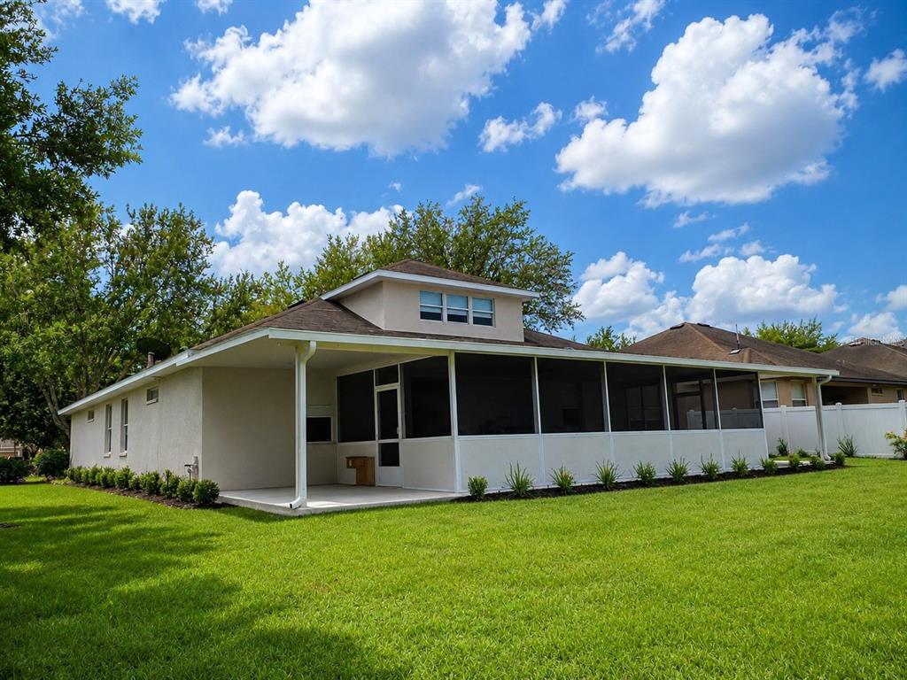 The exterior of a house features a large screened-in patio and a grassy backyard — 1124 FENNEL GREEN DR, SEFFNER, FL
