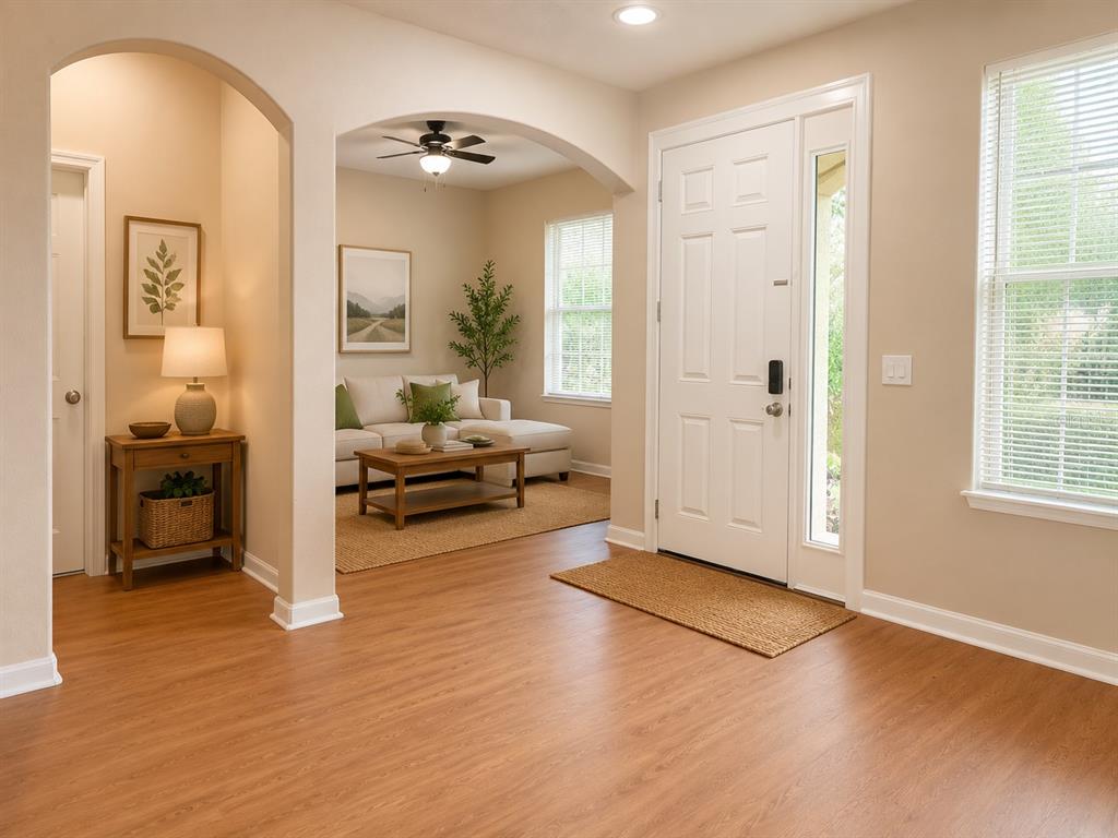 An entryway with wood-look flooring leads to a living area featuring an arched opening — 1124 FENNEL GREEN DR, SEFFNER, FL