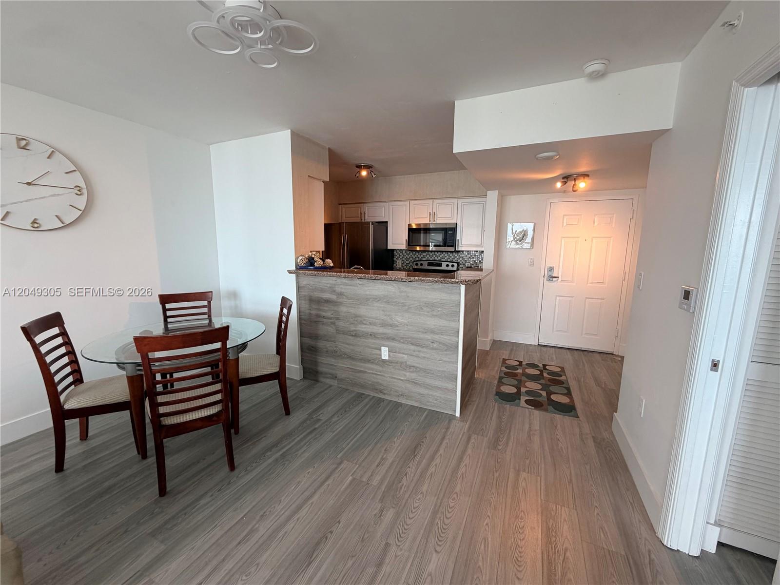 A dining area with a glass table and a kitchen featuring a wood-paneled breakfast bar — 1155 Brickell Bay Dr # 3405, Miami FL 33131, MIAMI, FL