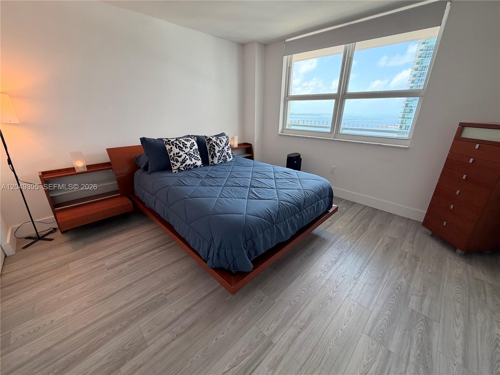 A bedroom features a platform bed, wooden furniture, and a large window with ocean views — 1155 Brickell Bay Dr # 3405, Miami FL 33131, MIAMI, FL