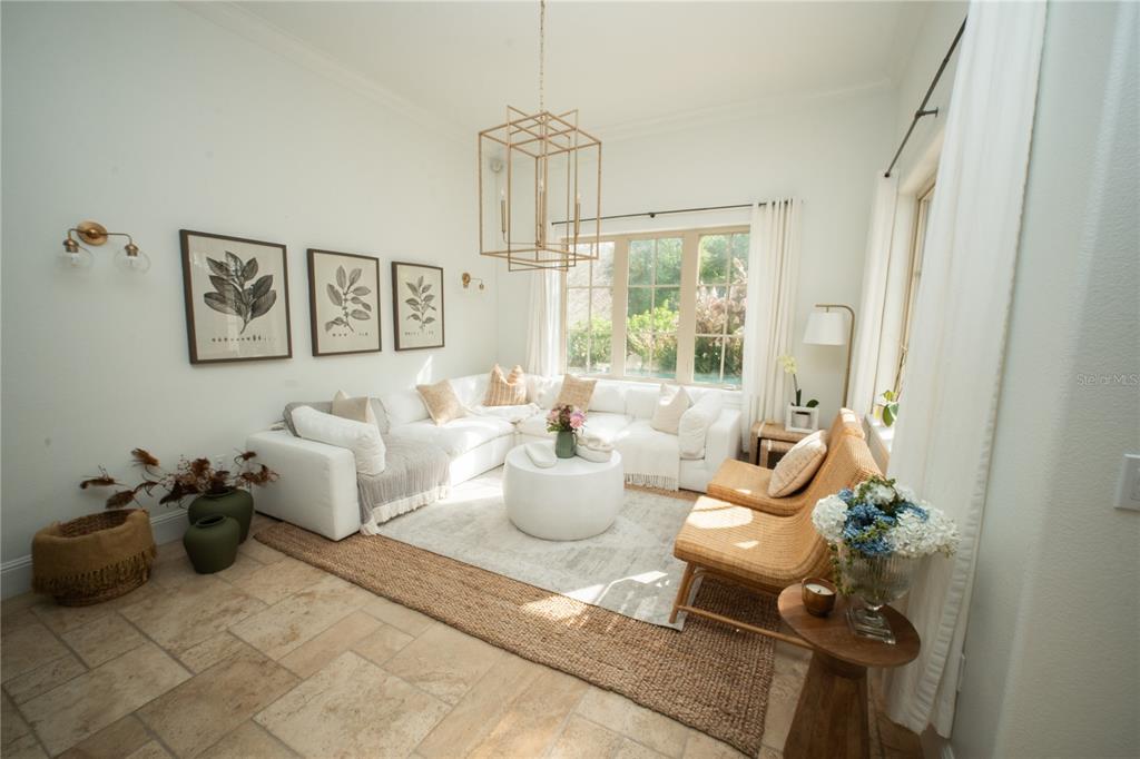 A bright living room features a white sectional sofa, wicker chairs, and a gold chandelier — 719 EASTLAWN DRIVE, KISSIMMEE, FL