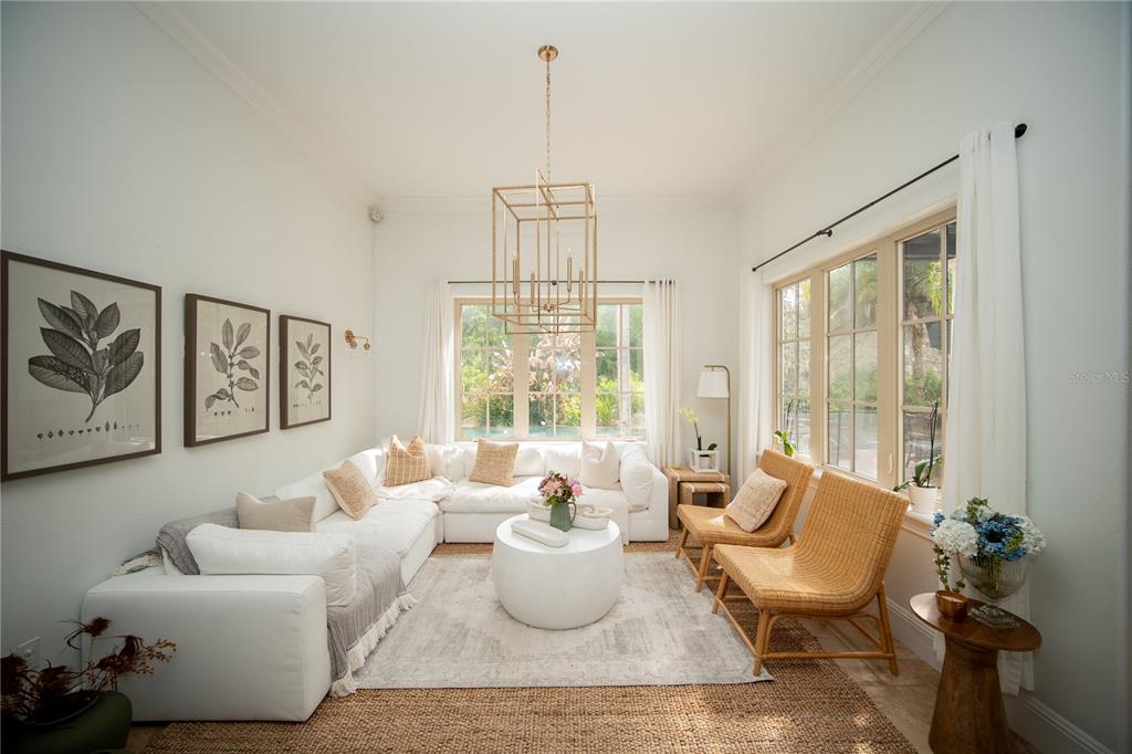 A bright living room features a white sectional sofa, two rattan chairs, and a chandelier — 719 EASTLAWN DRIVE, KISSIMMEE, FL