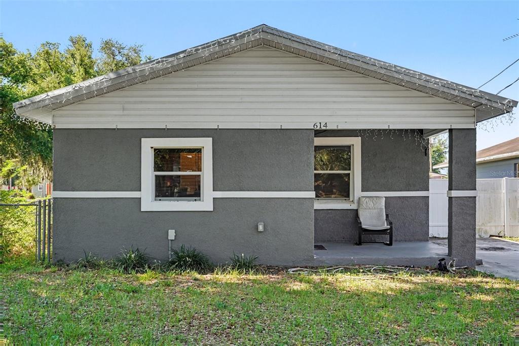 A single-story house with gray stucco siding, a front porch, and white trim — 614 W 6TH STREET, LAKELAND, FL